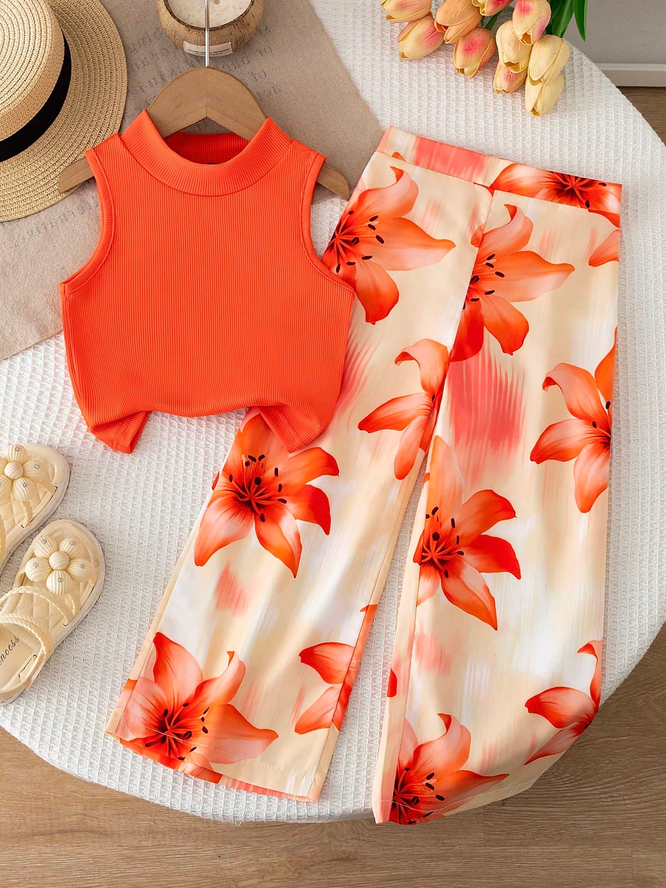 SHEIN Spring/Summer 2-Piece Girls' Clothing Set, Orange Sleeveless Mock Neck Tank Top + Orange Lily Print Wide Leg Pants, Mock Neck Sleeveless Design Simple And Crisp Suitable For Summer, Solid Color Top Simple And Elegant; Bottom Large Lily Print Bright And Eye-Catching, Overall Color Scheme Warm And Energetic, Style Fresh And Casual, Suitable For Daily Outings, Amusement Parks, Gatherings, Parent-Child Activities And Other Occasions.